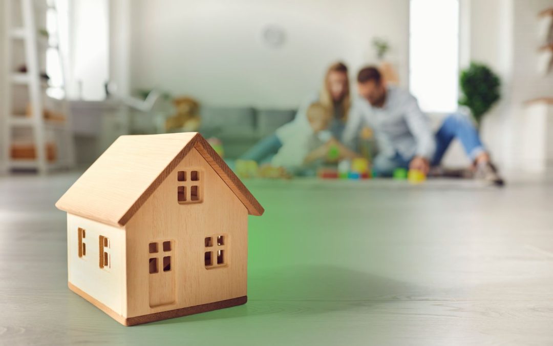 A model home on the floor with a family playing in the background, illustrating an Elite Mold Services guide on hidden mold symptoms in kids.