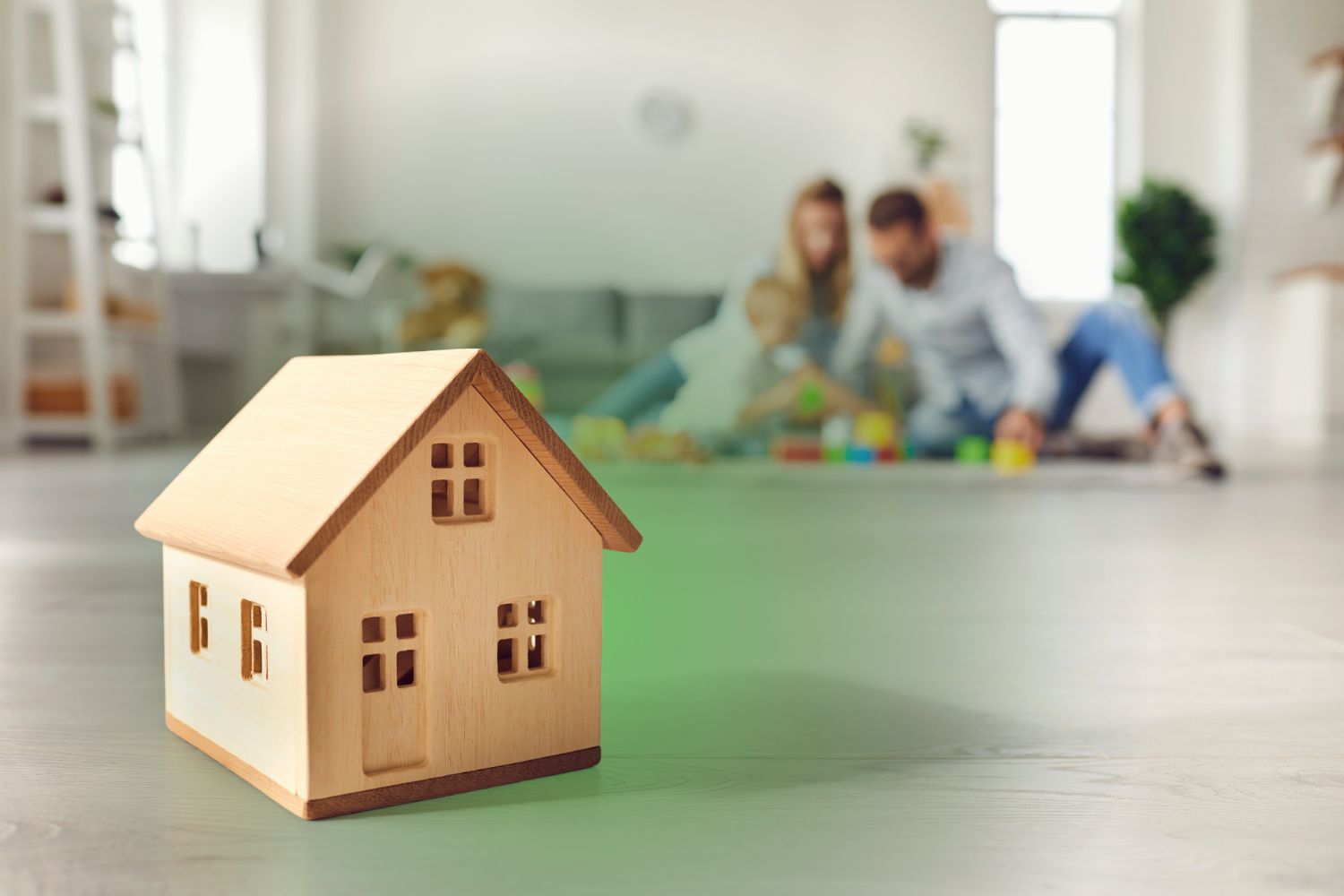 A model home on the floor with a family playing in the background, illustrating an Elite Mold Services guide on hidden mold symptoms in kids.